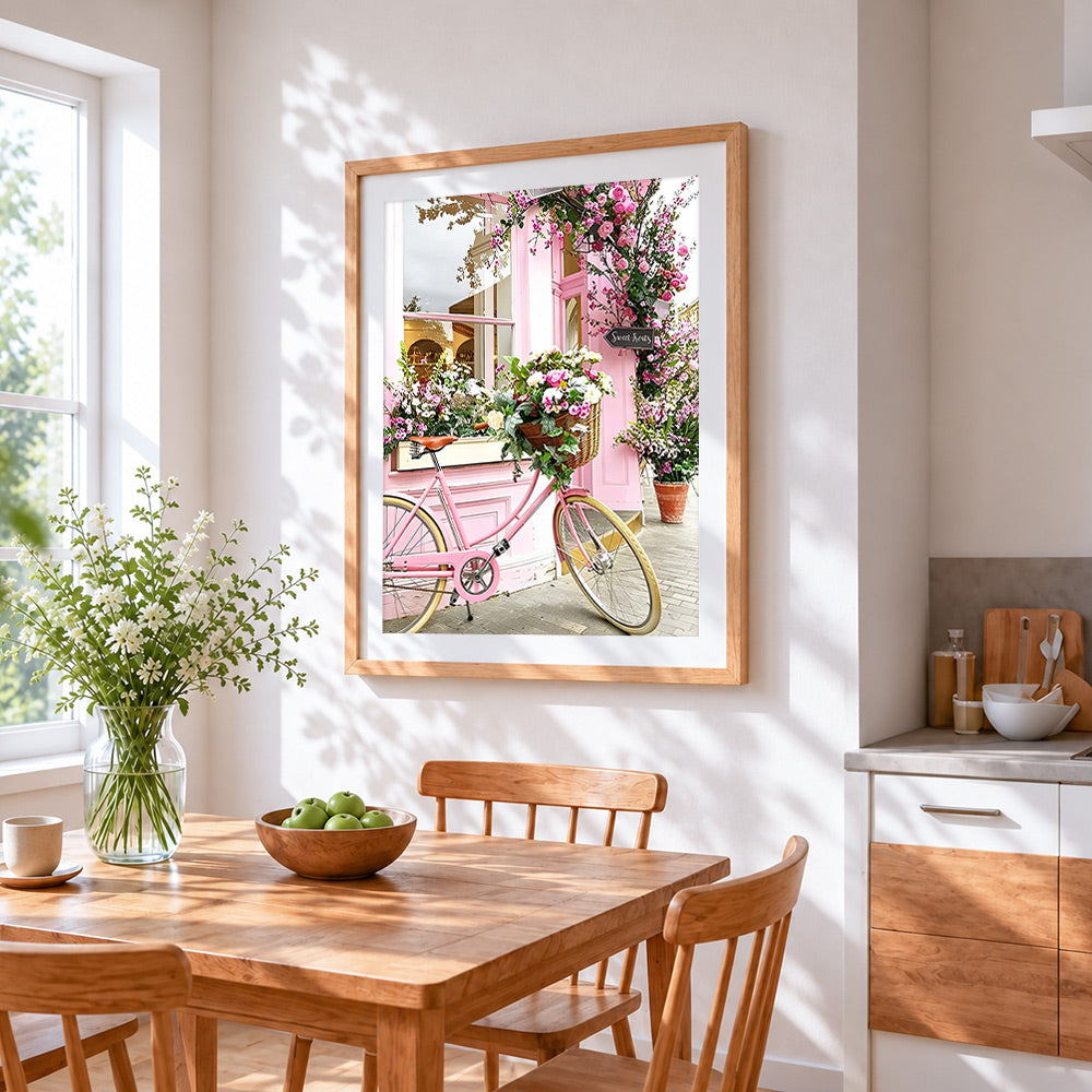 Pink bicycle with flower basket cross stitch artwork displayed on wall as home decor