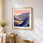 Pink mountain lake cross stitch artwork displayed on wall as home decor