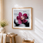 Pink orchid on black stones cross stitch artwork displayed on wall as home decor