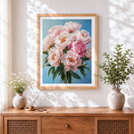 Finished pink peonies on a blue background cross stitch artwork displayed