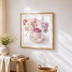 Pink rose in a teacup with macarons cross stitch artwork displayed on wall as home decor