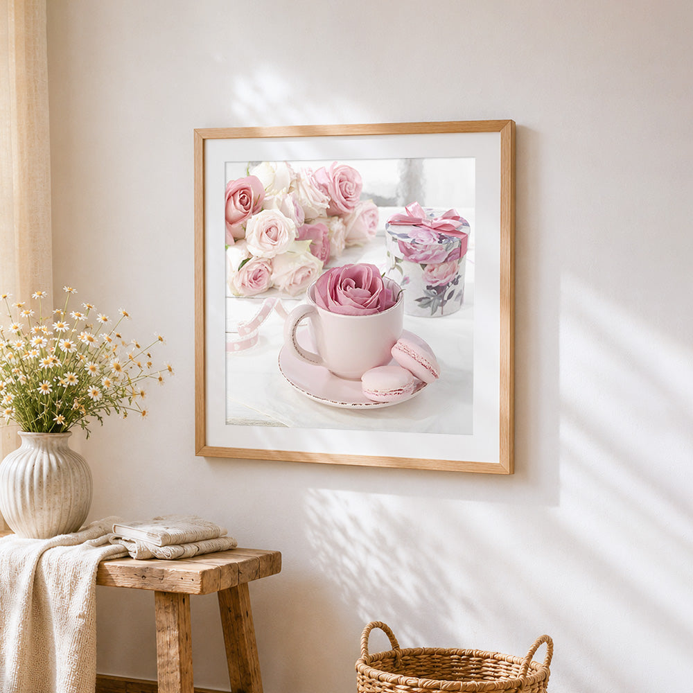Pink rose in a teacup with macarons cross stitch artwork displayed on wall as home decor