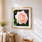 Pink rose with green leaves cross stitch artwork displayed on wall as home decor