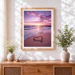 Finished pink sunset shoreline with sand heart cross stitch artwork displayed