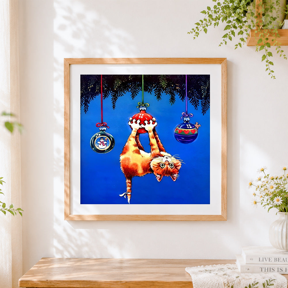 Finished playful cat hanging from christmas baubles cross stitch artwork displayed