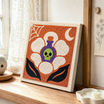 Poison skull blossom punch needle artwork displayed on a table