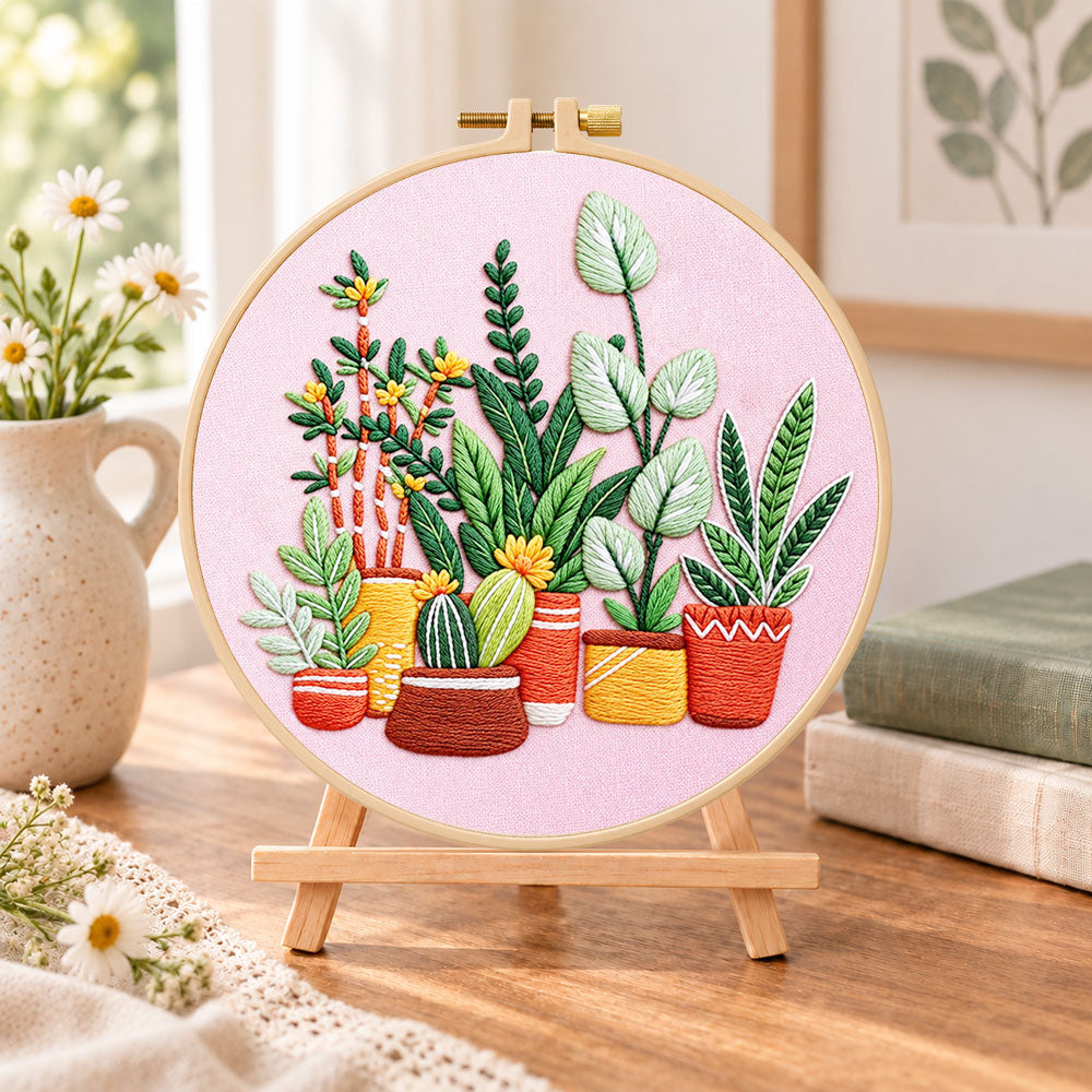 Potted plants on pink fabric embroidery kit finished hoop displayed on a wooden stand as cosy tabletop decor