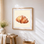 Powdered sugar croissant cross stitch artwork displayed on wall as home decor