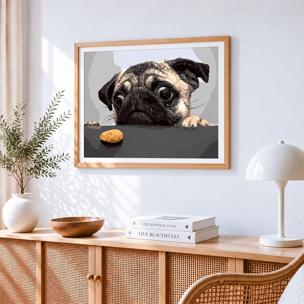 Pug with a biscuit cross stitch artwork displayed on wall as home decor