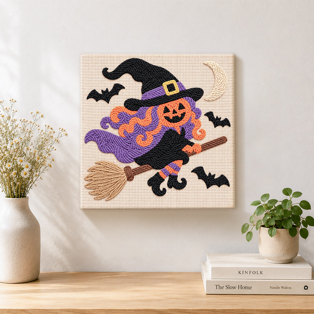 Pumpkin witch on broom punch needle artwork displayed on a table