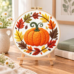 Pumpkin wreath with fall foliage embroidery kit finished hoop displayed on a wooden stand as cosy tabletop decor