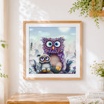 Finished purple fantasy owl and baby cross stitch artwork displayed