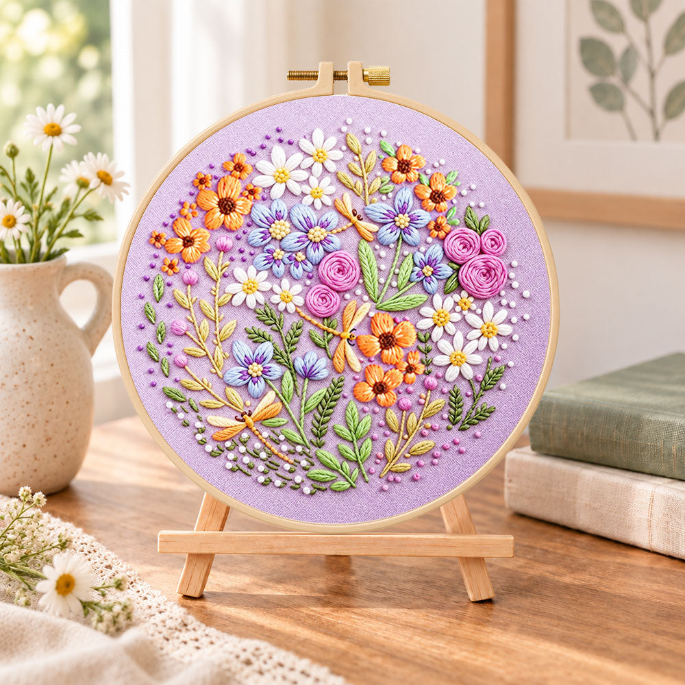 Purple floral circle with dragonflies embroidery kit finished hoop displayed on a wooden stand as cosy tabletop decor