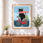Finished quirky black cat on bicycle cross stitch artwork displayed