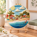 Radiant coastal hamlet embroidery kit finished hoop displayed on a wooden stand as cosy tabletop decor