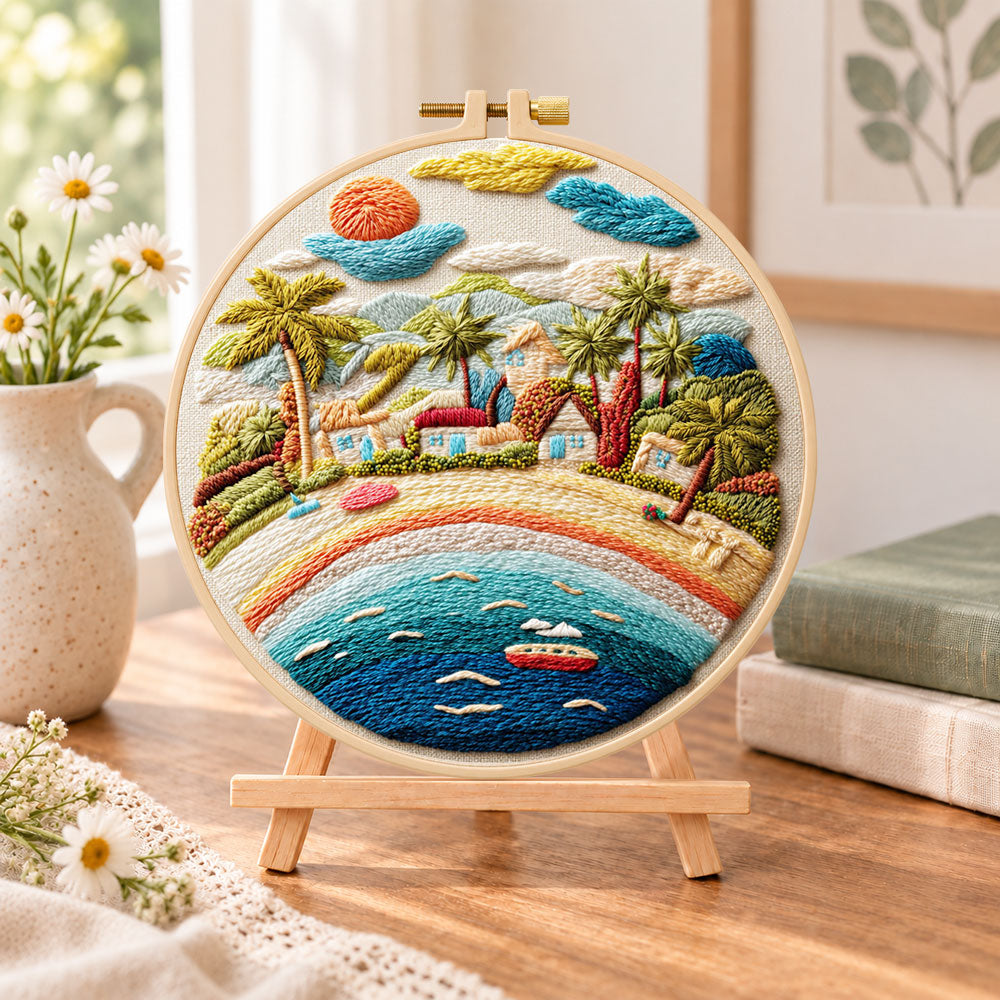 Rainbow seaside village embroidery kit finished hoop displayed on a wooden stand as cosy tabletop decor