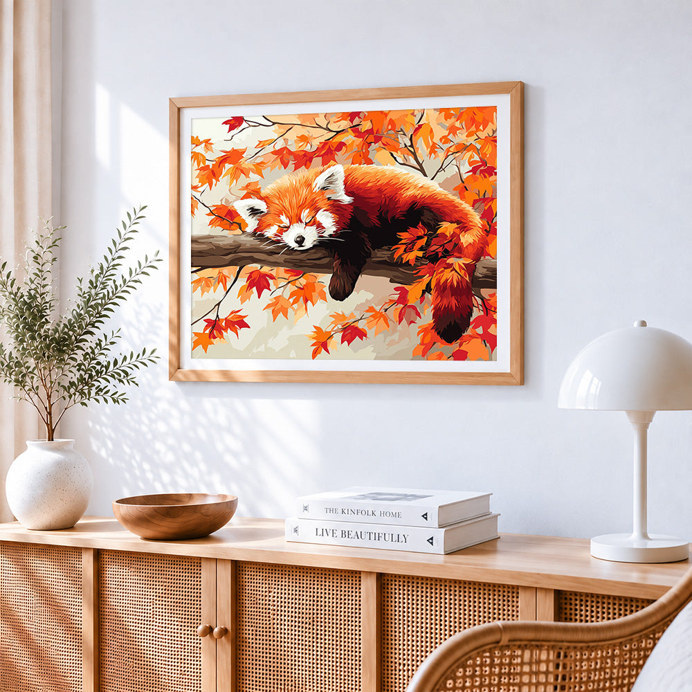 Red panda sleeping in autumn leaves cross stitch artwork displayed on wall as home decor