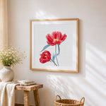 Red poppies with blue leaves cross stitch artwork displayed on wall as home decor
