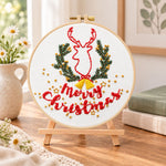 Reindeer and christmas text embroidery kit finished hoop displayed on a wooden stand as cozy tabletop decor