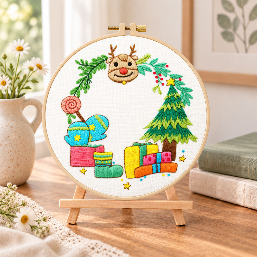 Reindeer and gifts scene embroidery kit finished hoop displayed on a wooden stand as cosy tabletop decor