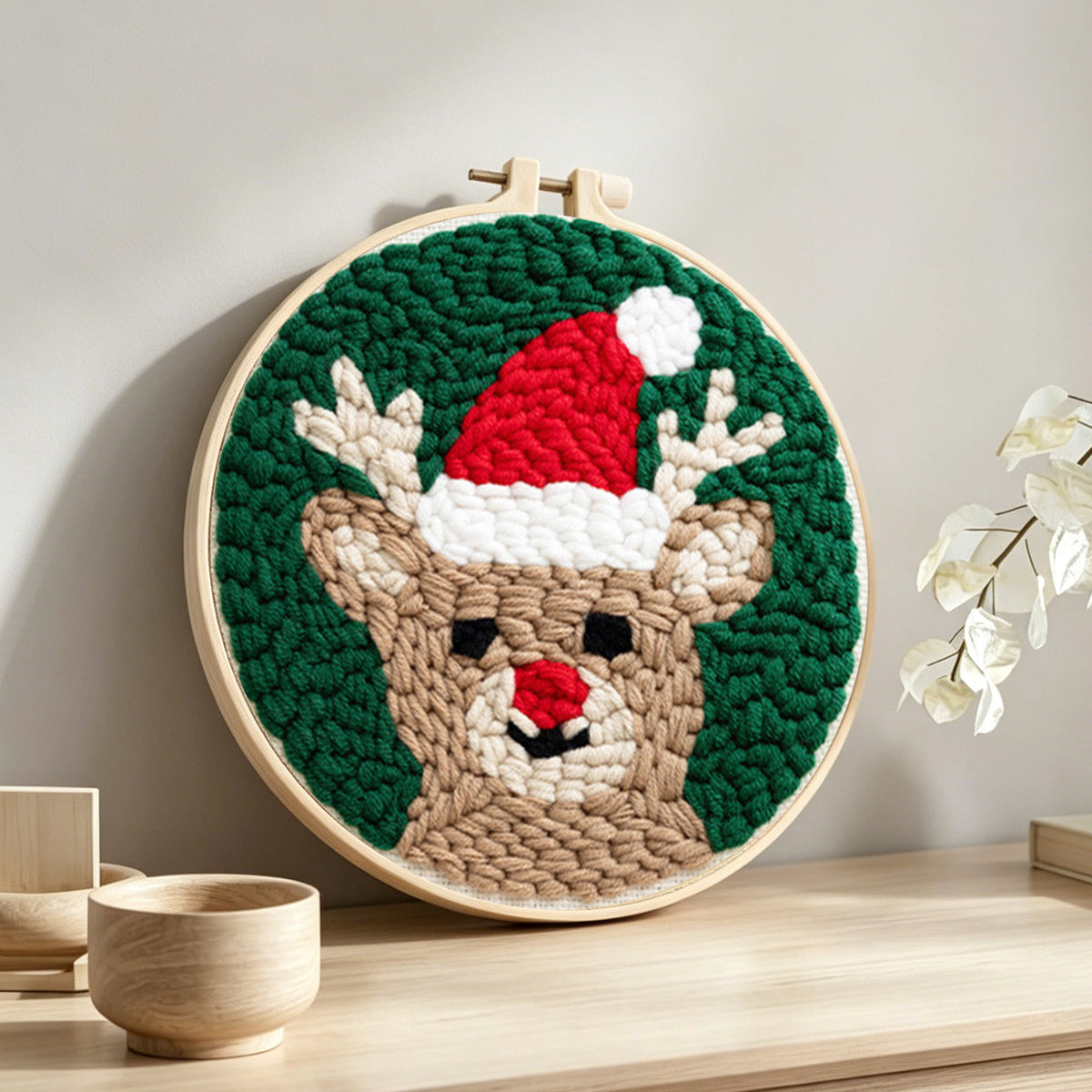 Reindeer with santa hat punch needle artwork displayed on a table