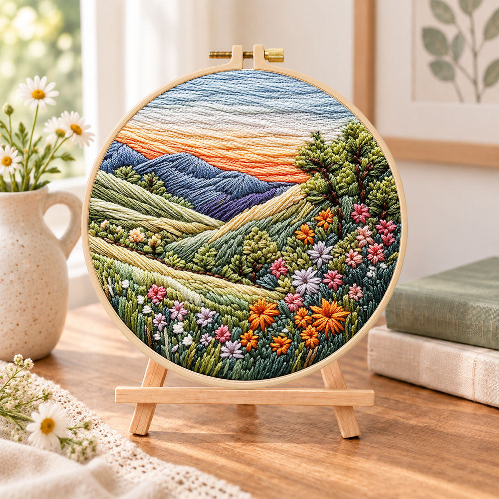 Rolling hills floral vista embroidery kit finished hoop displayed on a wooden stand as cozy tabletop decor