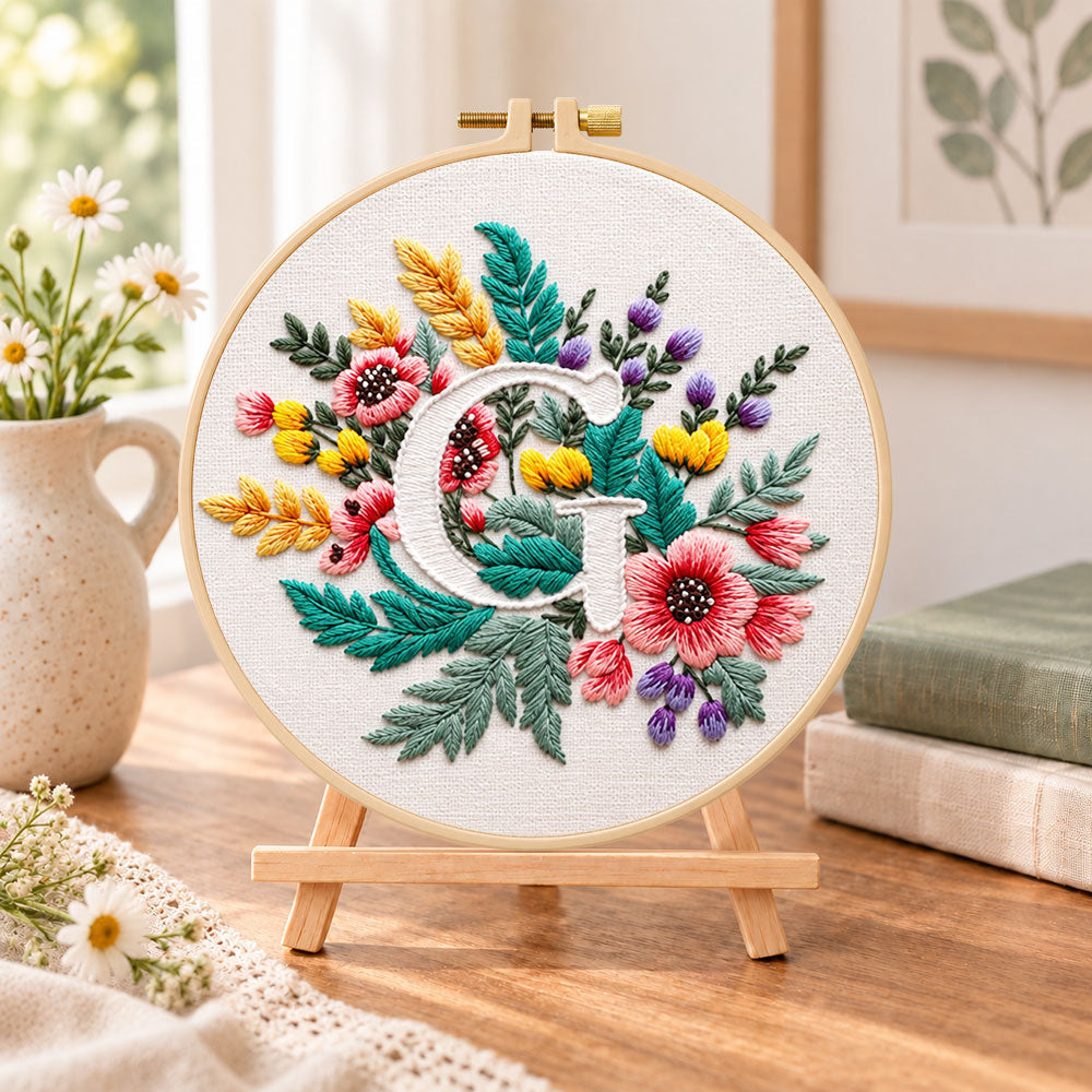 Rustic floral mix and letter g embroidery kit finished hoop displayed on a wooden stand as cosy tabletop decor