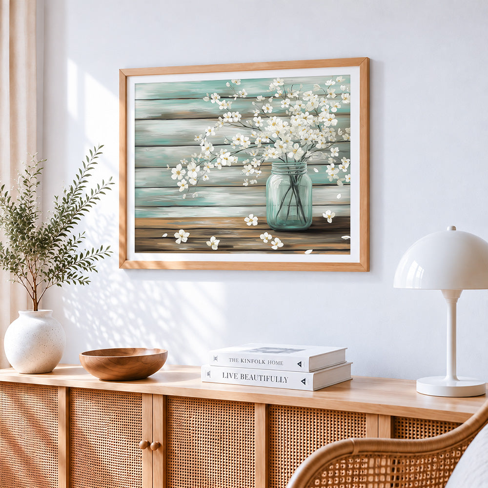 Rustic mason jar with white blossoms cross stitch artwork displayed on wall as home decor