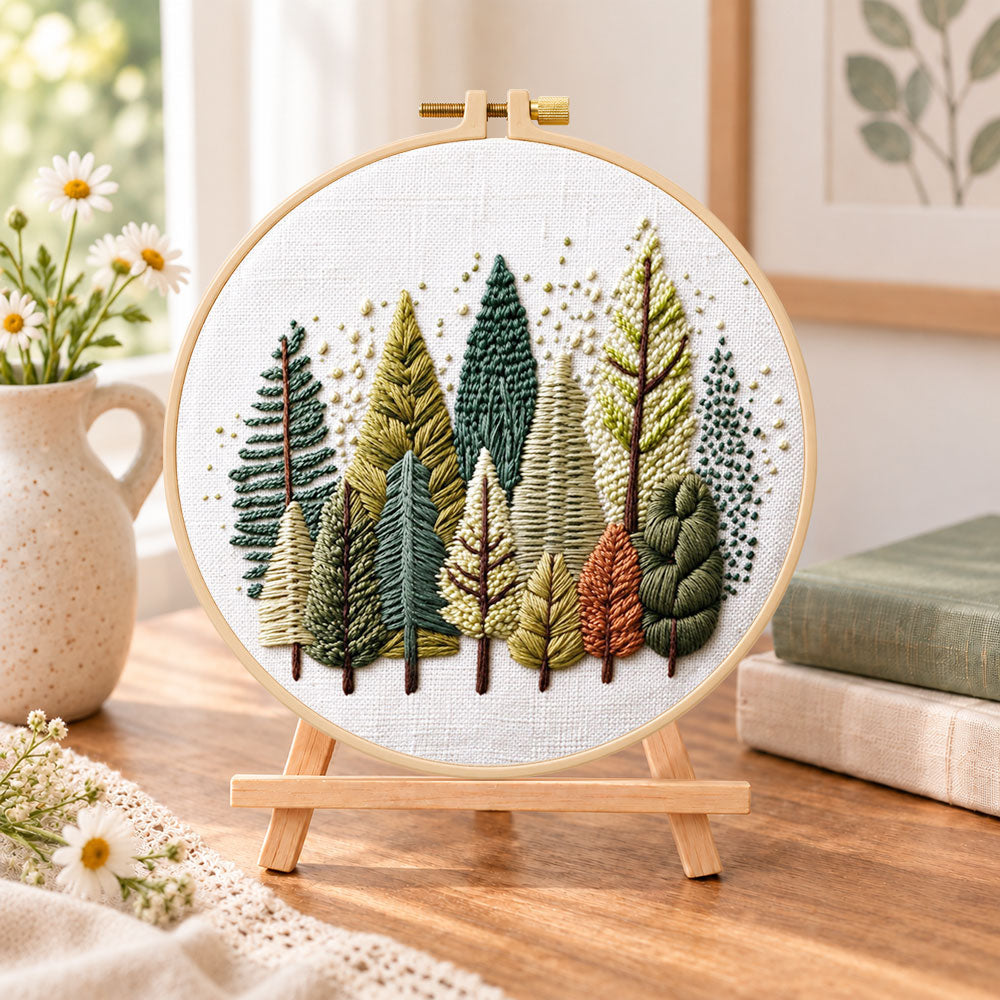 Rustic pine tree grove embroidery kit finished hoop displayed on a wooden stand as cosy tabletop decor
