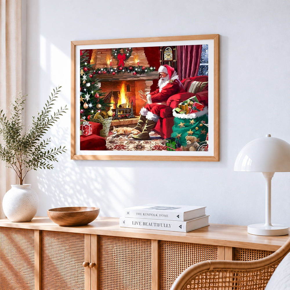 Santa relaxing by the fire with cat cross stitch artwork displayed on wall as home decor