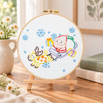 Santa sleigh ride embroidery kit finished hoop displayed on a wooden stand as cosy tabletop decor