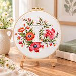 Scarlet florals and letter t embroidery kit finished hoop displayed on a wooden stand as cosy tabletop decor
