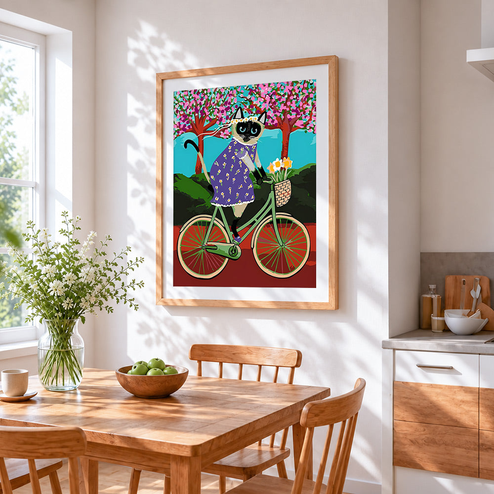 Siamese cat riding a bicycle cross stitch artwork displayed on wall as home decor