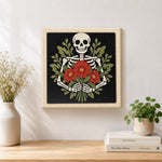 Finished skeleton holding red blooms artwork displayed on a wall