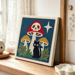Skull mushroom and black cat punch needle artwork displayed on a table