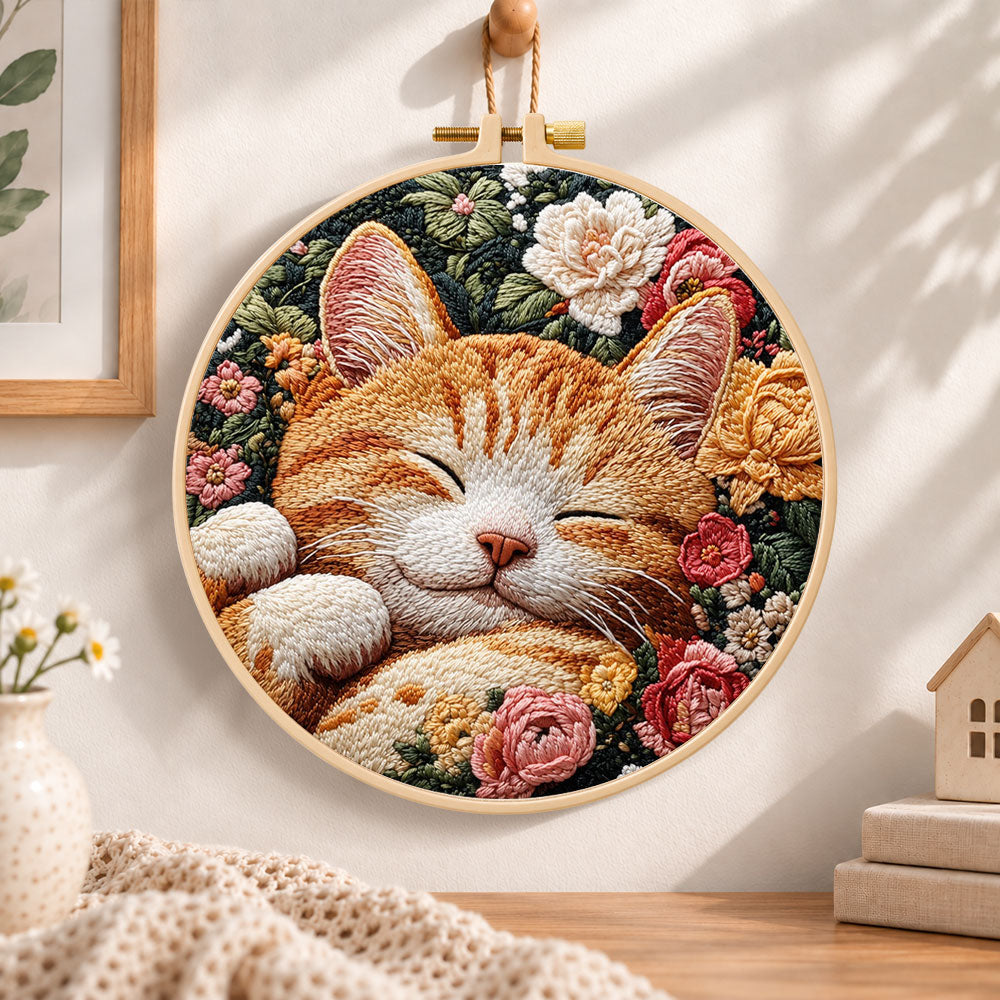 Sleeping ginger cat among roses embroidery hoop wall art displayed as warm and cozy handmade home decor