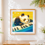 Finished sleepy panda on a piano keyboard cross stitch artwork displayed