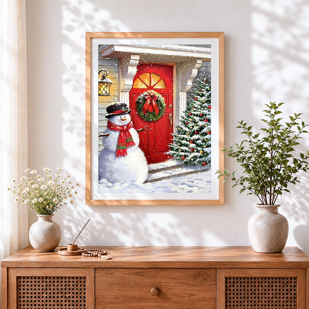 Finished snowman by a red door with christmas tree cross stitch artwork displayed
