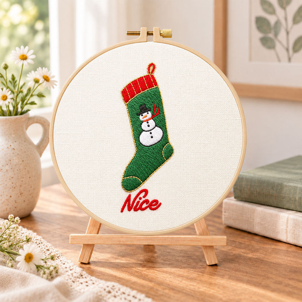 Snowman christmas stocking embroidery kit finished hoop displayed on a wooden stand as cozy tabletop decor