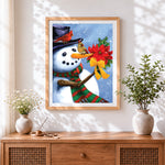 Finished snowman holding poinsettia cross stitch artwork displayed