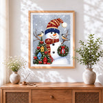 Finished snowman with knitted hat and birdhouse tree cross stitch artwork displayed