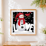Finished snowman with red bird cross stitch artwork displayed
