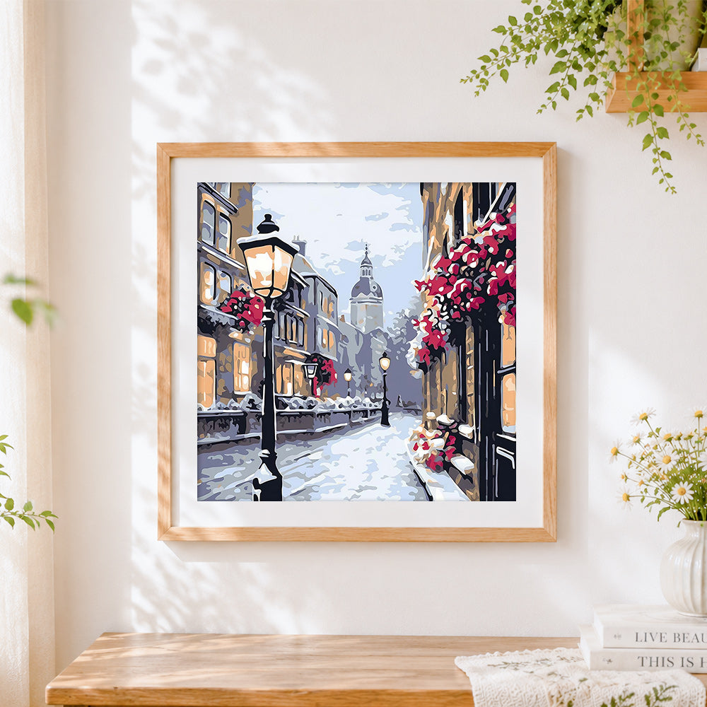Finished snowy european street cross stitch artwork displayed