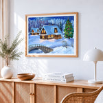 Snowy log cabins and christmas tree in winter forest cross stitch artwork displayed on wall as home decor