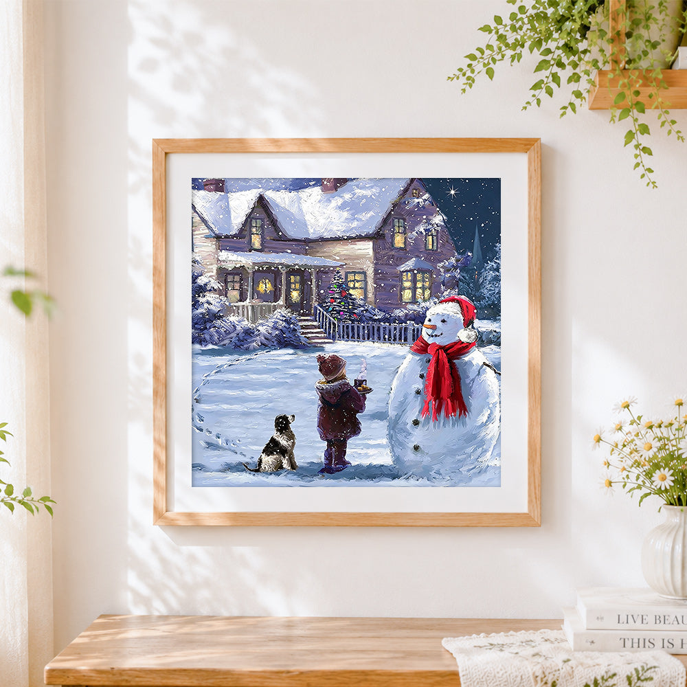 Finished snowy night cottage and snowman cross stitch artwork displayed