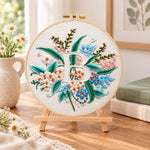 Soft pastel blooms and letter b embroidery kit finished hoop displayed on a wooden stand as cosy tabletop decor
