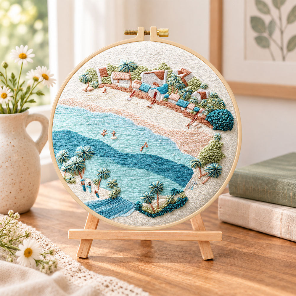 Soft seaside town embroidery kit finished hoop displayed on a wooden stand as cosy tabletop decor