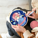Creating handmade space girl sitting on a planet punch needle artwork
