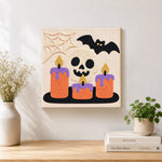 Finished spooky skull candles artwork displayed on a wall