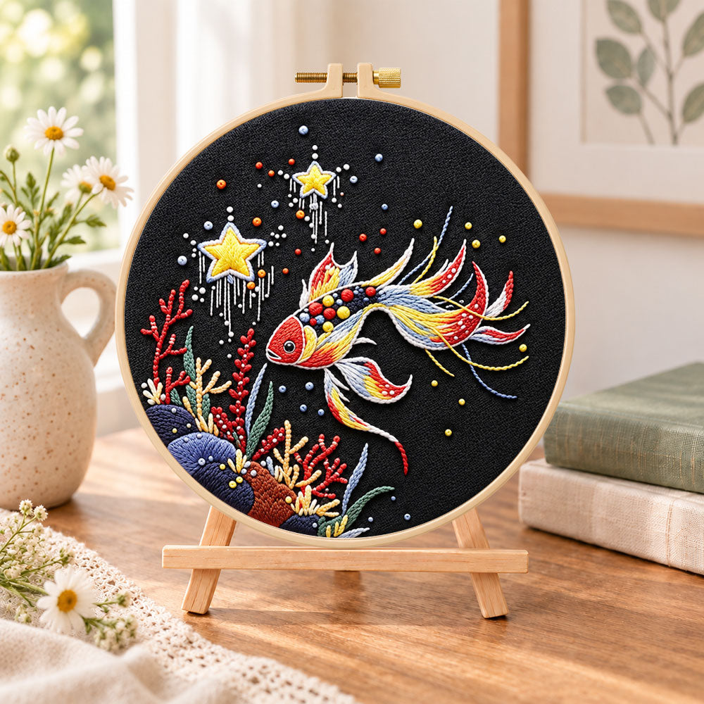 Star and coral koi embroidery kit finished hoop displayed on a wooden stand as cosy tabletop decor